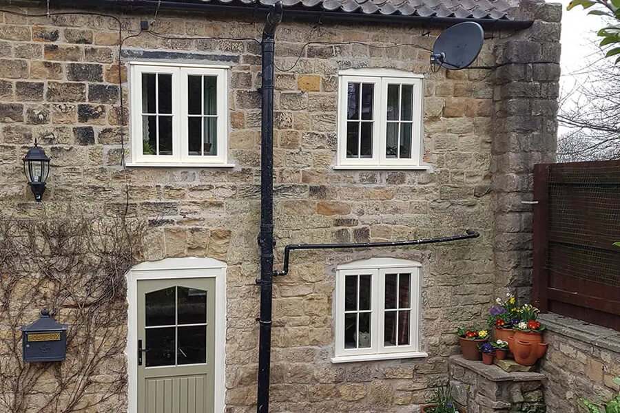 House with stone walls and white lipped casement windows