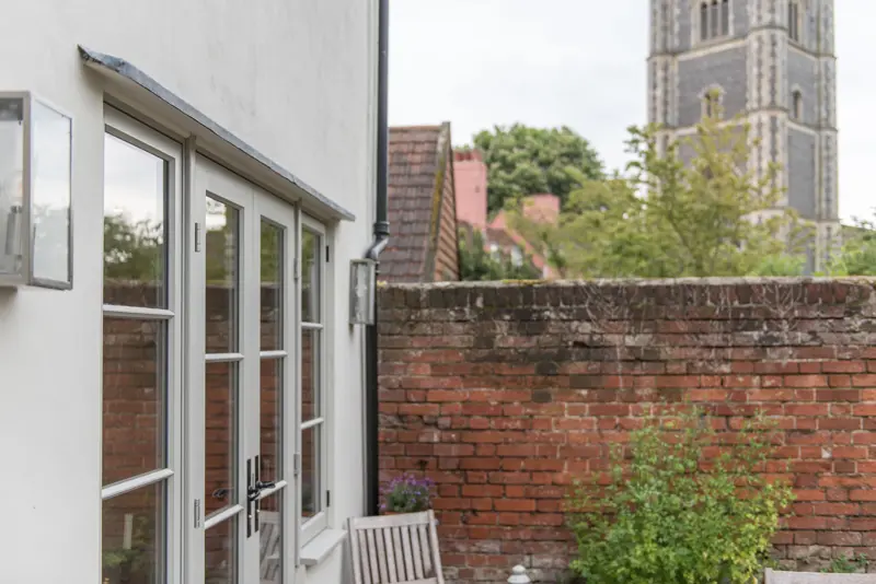 Grey French doors with view of church over a garden wall