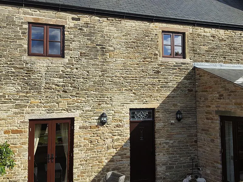 Converted barn with dark stained timber windows and doors