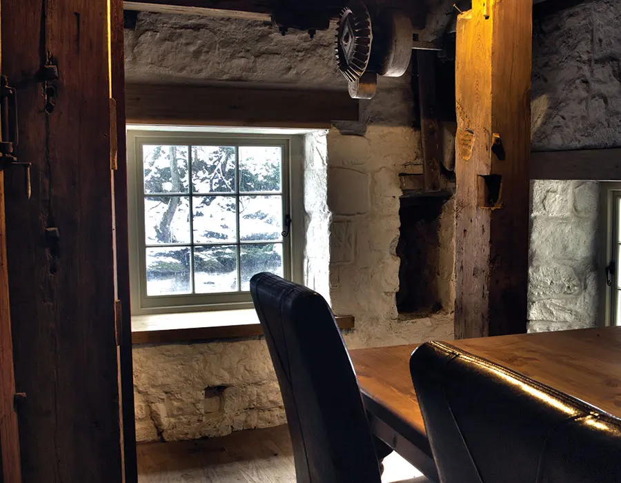 Home with stone walls with a flush timber casement window looking out to a snowy garden