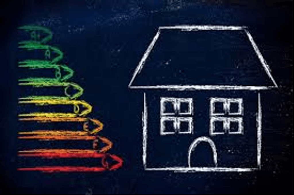 A chalk-drawn house beside a vertical energy efficiency scale labeled A to G, with colors ranging from green (top) to red (bottom), on a blackboard background.